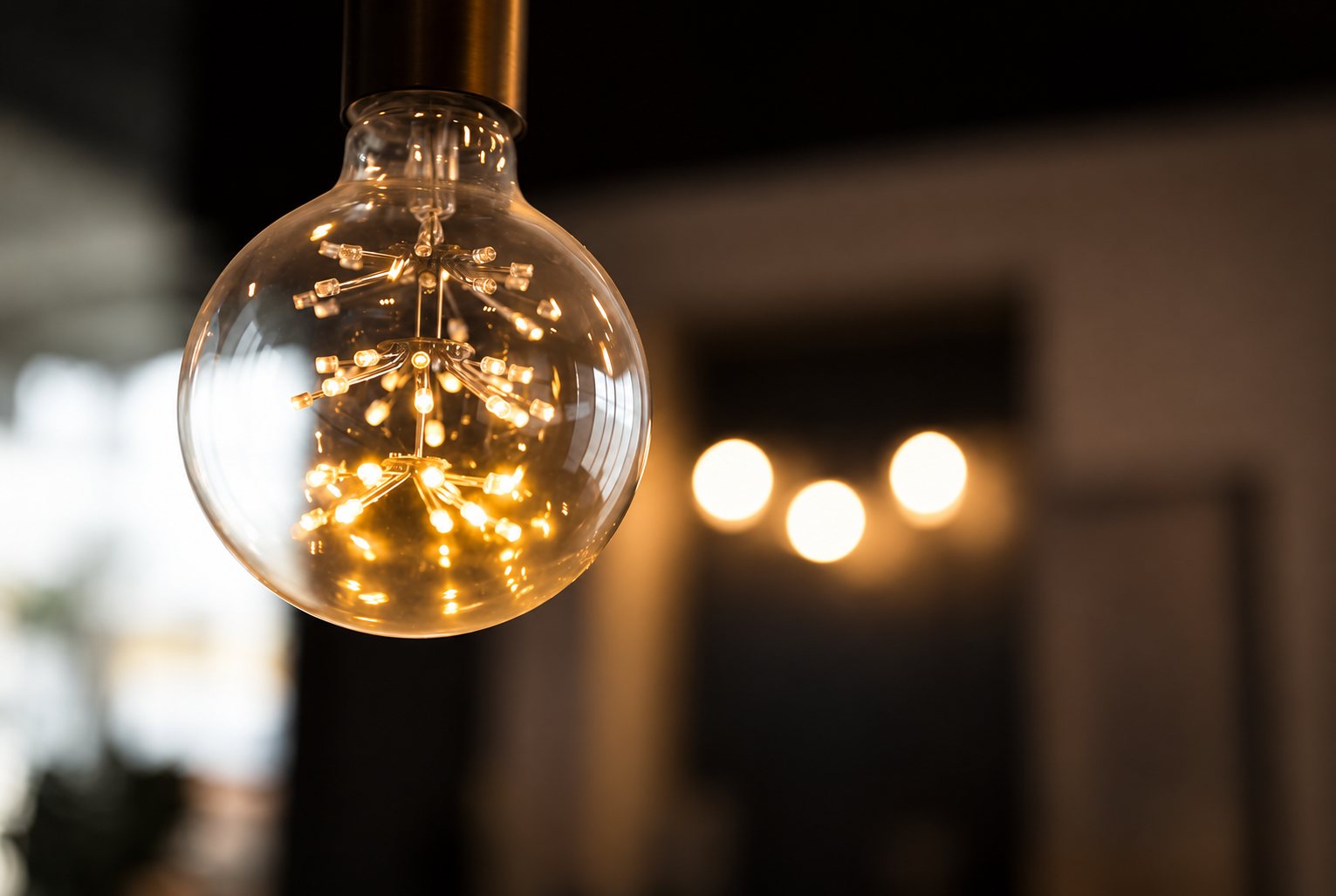 Gros plan sur une ampoule globe en verre dont les petites LED disposées en étoile diffusent une lumière dorée, avec des lumières floues en arrière-plan.